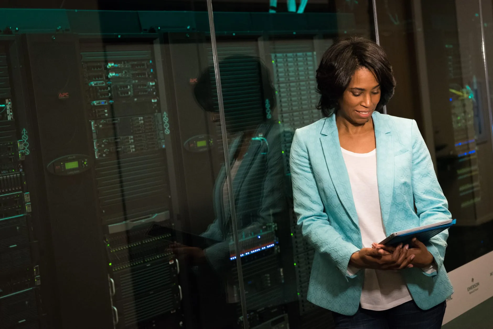 A person checking a tablet beside server racks, representing website maintenance, backups and support
